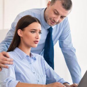 Man placing hand on uncomfortable coworker at laptop